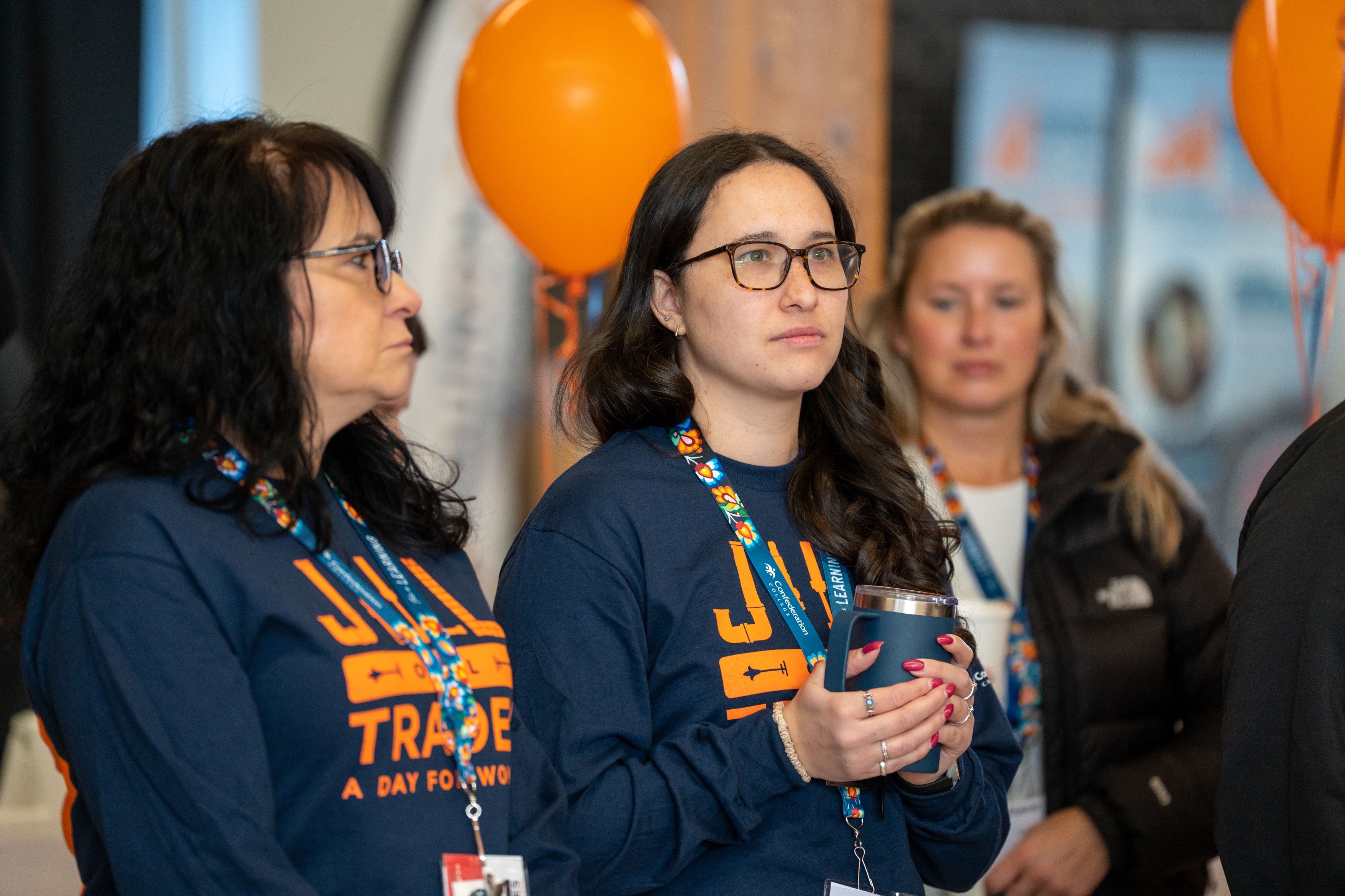 Attendees in “Jill of All Trades” shirts watching a presentation at a trades outreach event