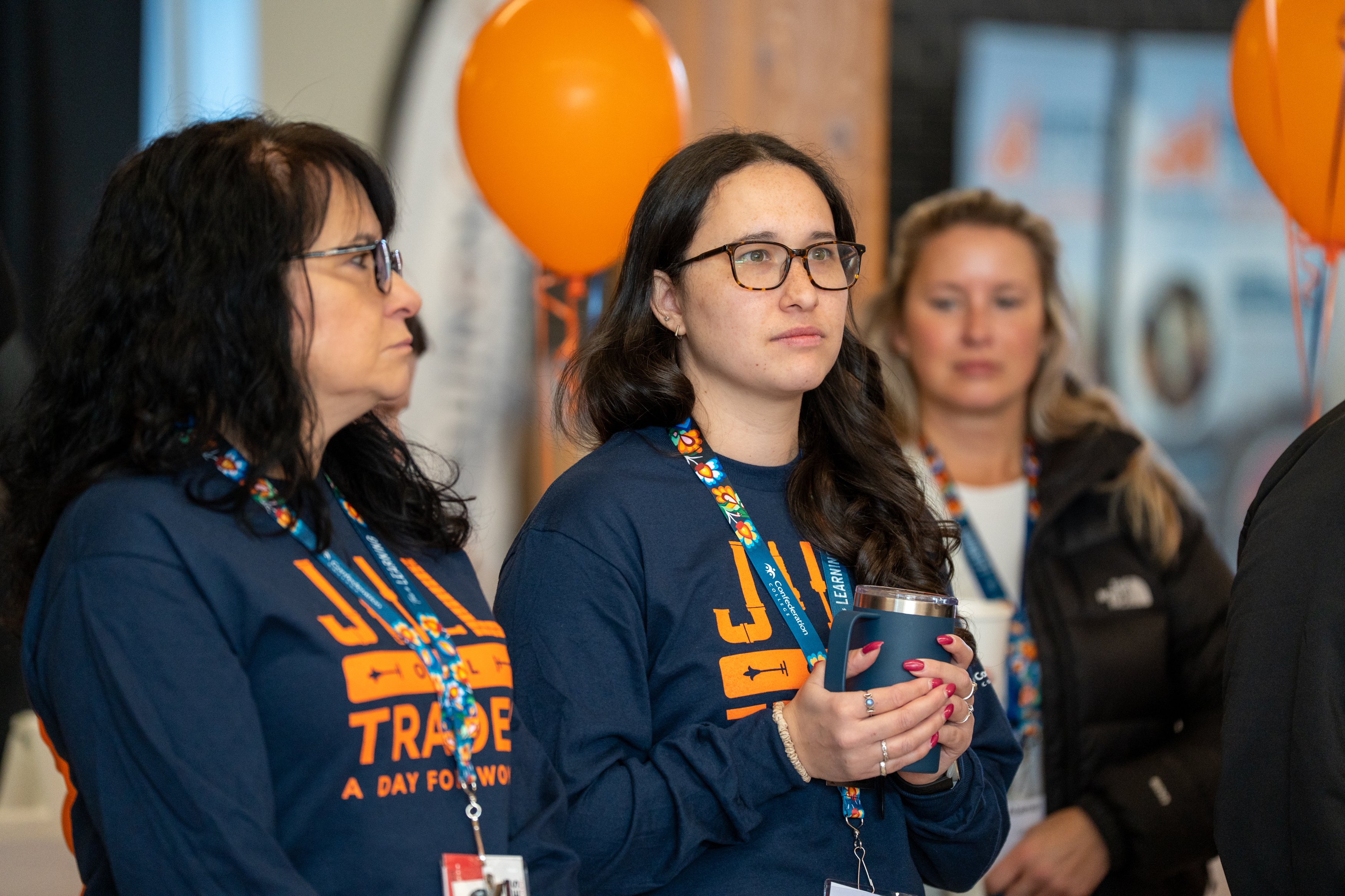 Attendees in “Jill of All Trades” shirts watching a presentation at a trades outreach event