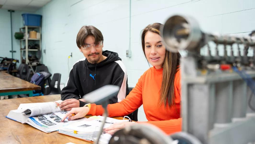 Instructor guiding a student through engine components in the lab