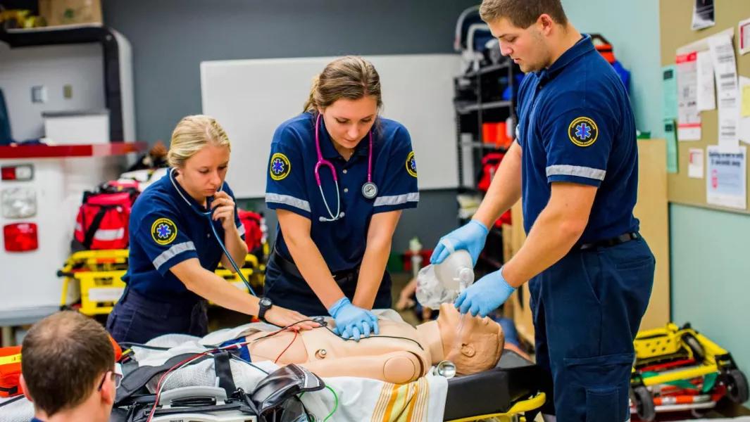 Team of paramedic trainees performing CPR and airway support in a lab setting