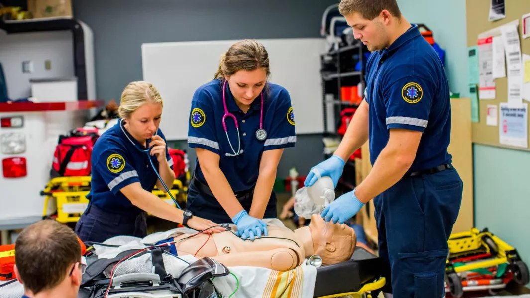 Team of paramedic trainees performing CPR and airway support in a lab setting
