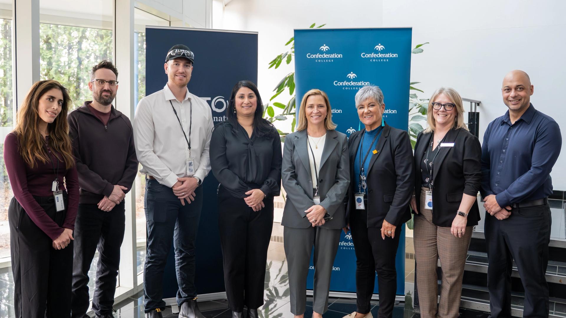 Group of persons posing indoors in front of Confederation College and Alstom banners during partnership announcement