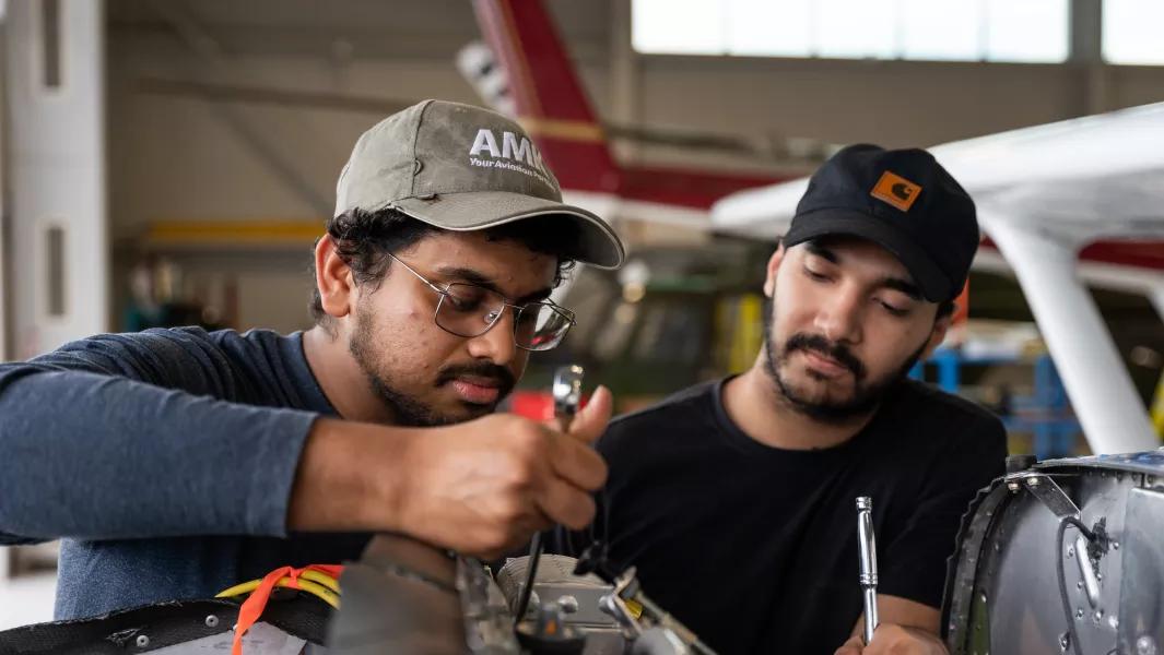 Two aviation students working on an aircraft engine in the hangar