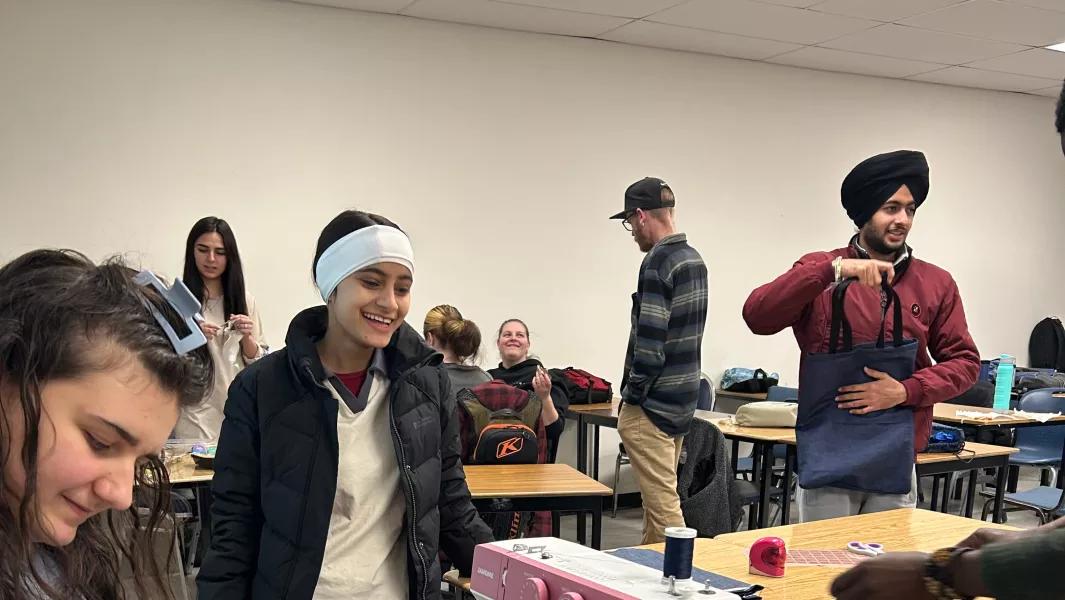Students socializing and working on sewing projects in class