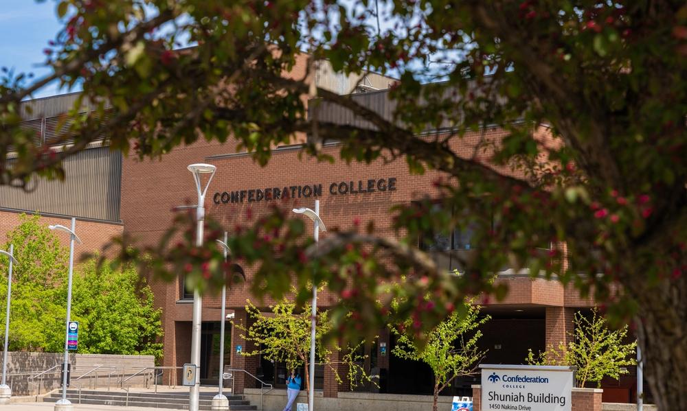 Thunder Bay campus Confederation College building with trees in the foreground and a Shuniah Building sign near the entrance