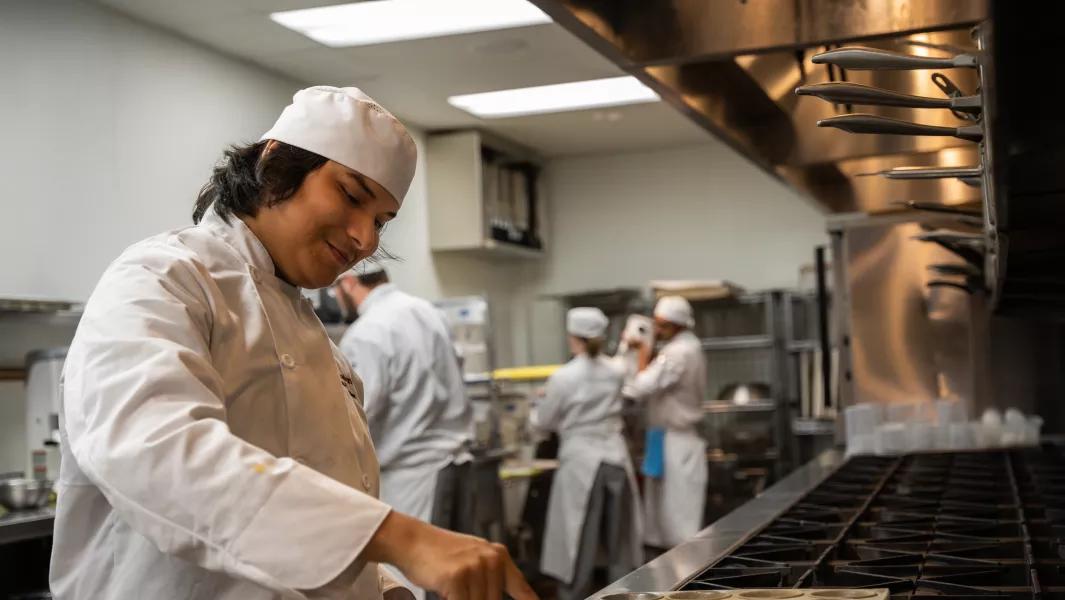 Culinary student cooking at the stovetop during kitchen lab
