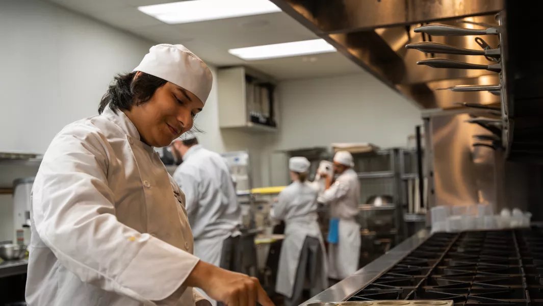 Culinary student cooking at the stovetop during kitchen lab