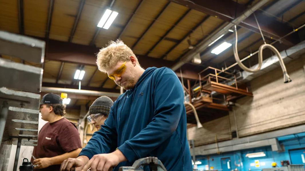 Students focused on hands-on mechanical work in a busy workshop