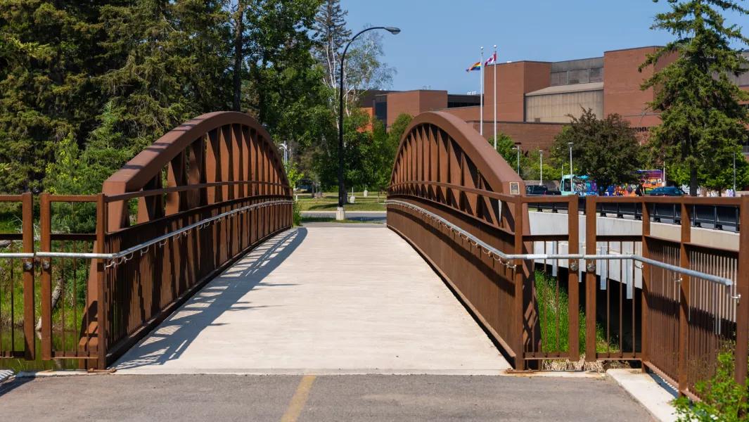 Pedestrian bridge leading across campus with buildings in the background