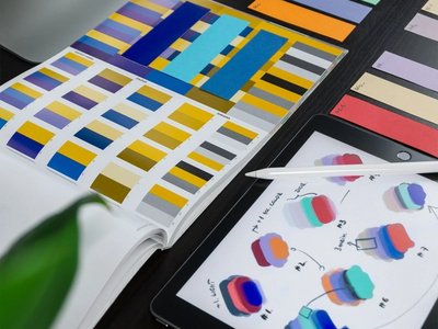Graphic design workspace with color palettes, swatches, and tablet-based colour scheme planning