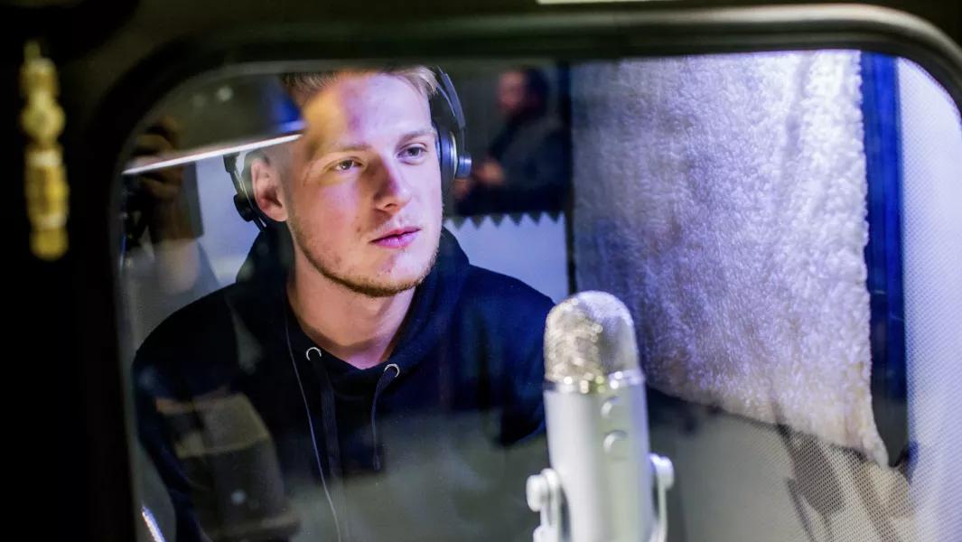 Student recording voice work in a sound booth