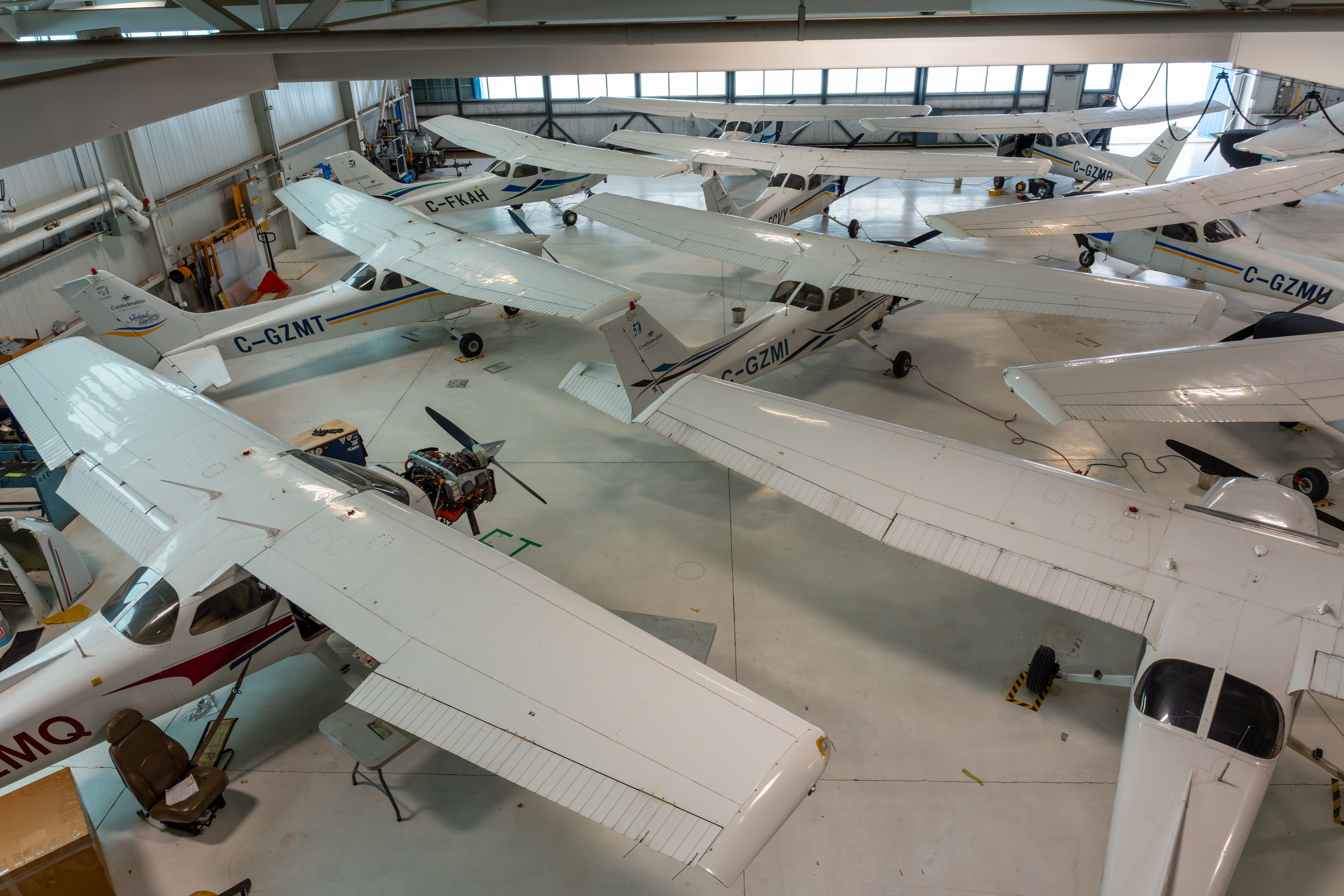 Several small training airplanes parked inside a hangar