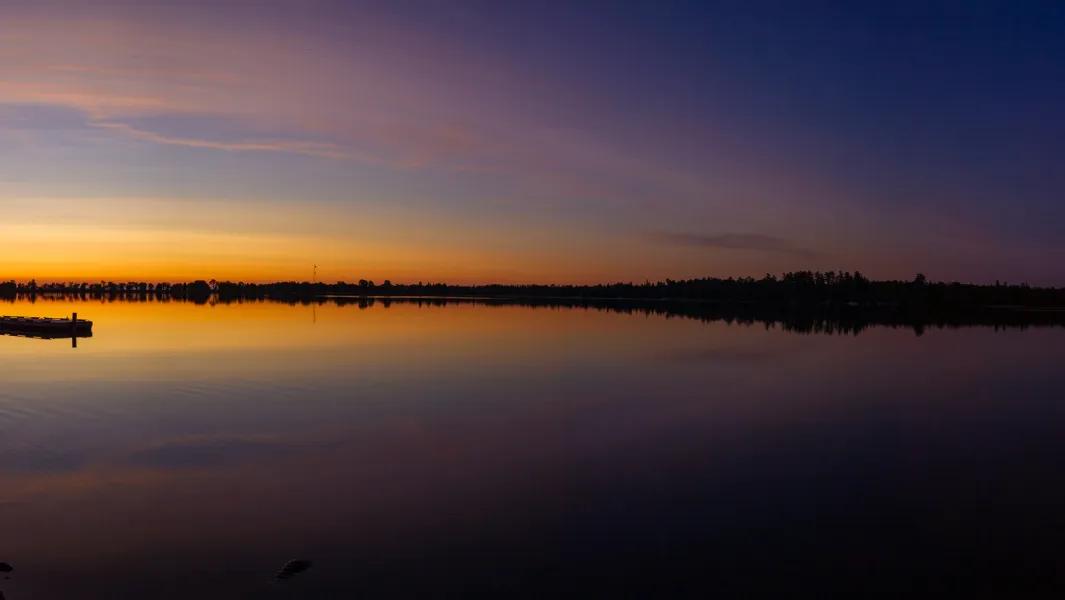 Calm lake at sunset with orange and purple sky reflected on the water