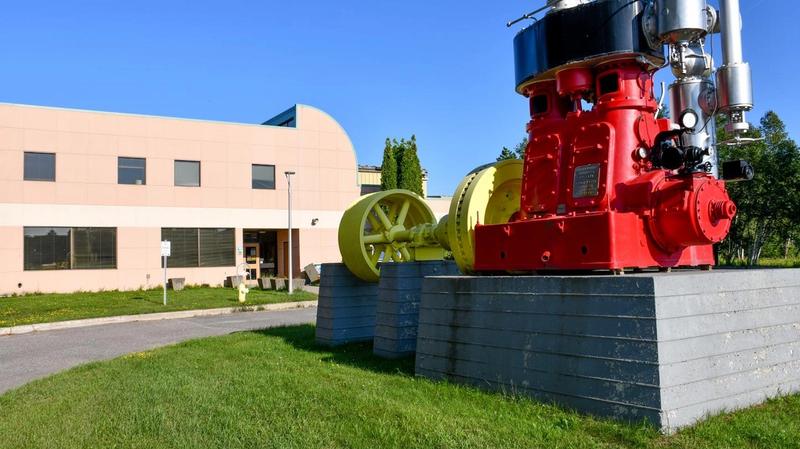 Dorion facility Red and yellow industrial machinery displayed outside a beige building under a clear blue sky