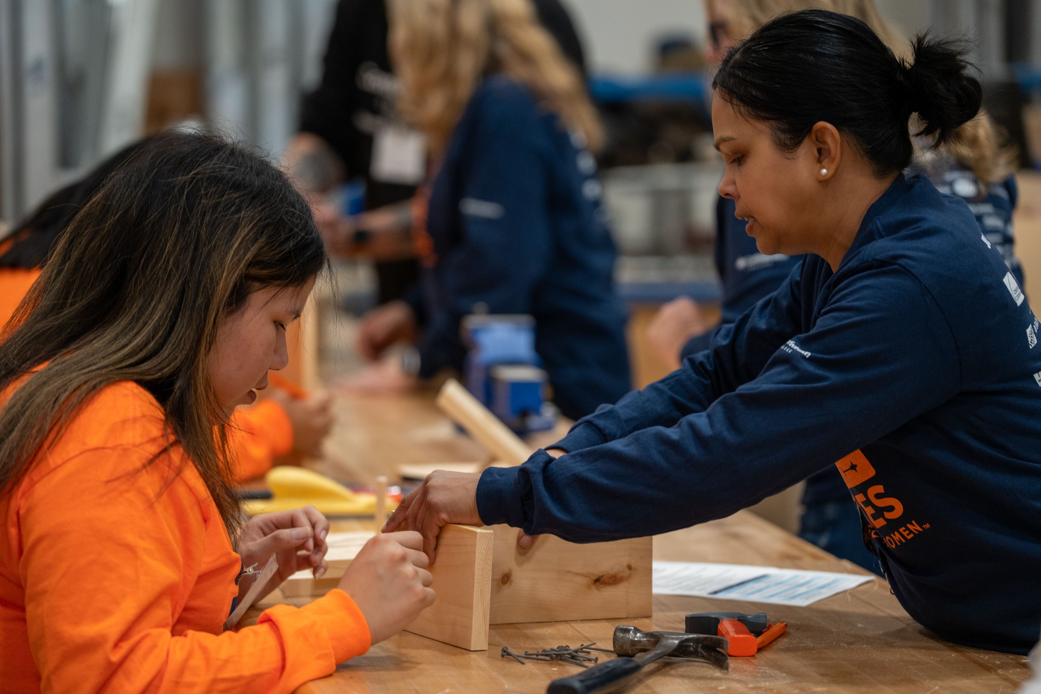 Participant helping a student assemble a small wood project during a hands-on trades workshop