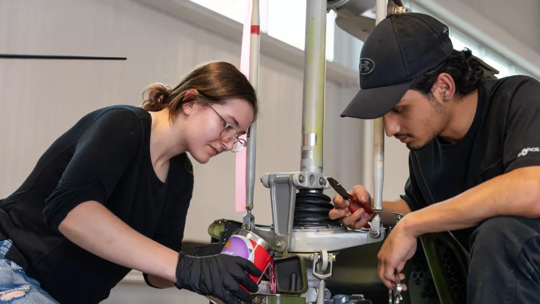 Students servicing an aircraft landing gear assembly in the hangar
