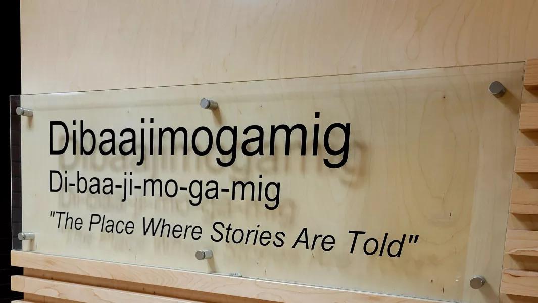 Wall sign reading “Dibaajimogamig – The Place Where Stories Are Told"