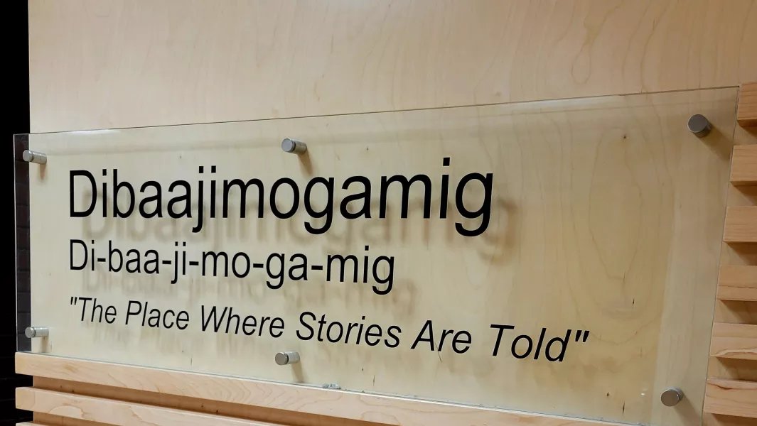 Wall sign reading “Dibaajimogamig – The Place Where Stories Are Told"