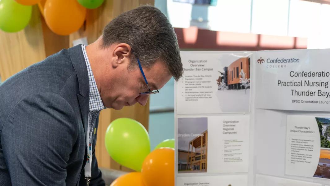 Staff member viewing a Practical Nursing program display at a Confederation College event