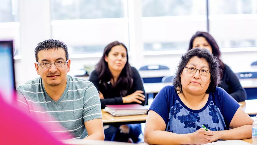 Adult learners sitting in a classroom attentively listening