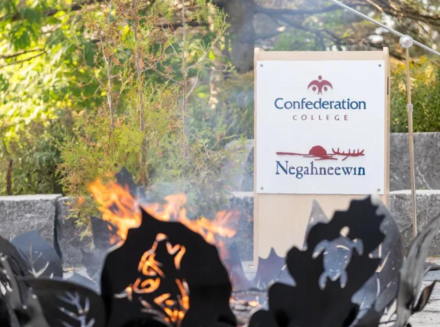 Confederation College Negahneewin sign behind a fire pit outdoors