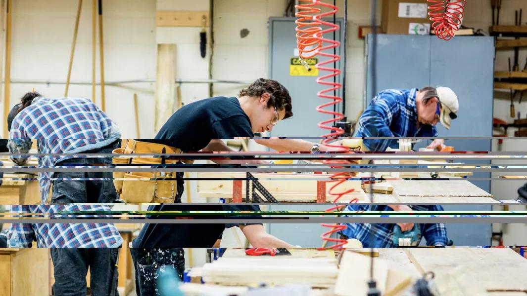 Carpentry students assembling and sanding wood projects during a practical lab session