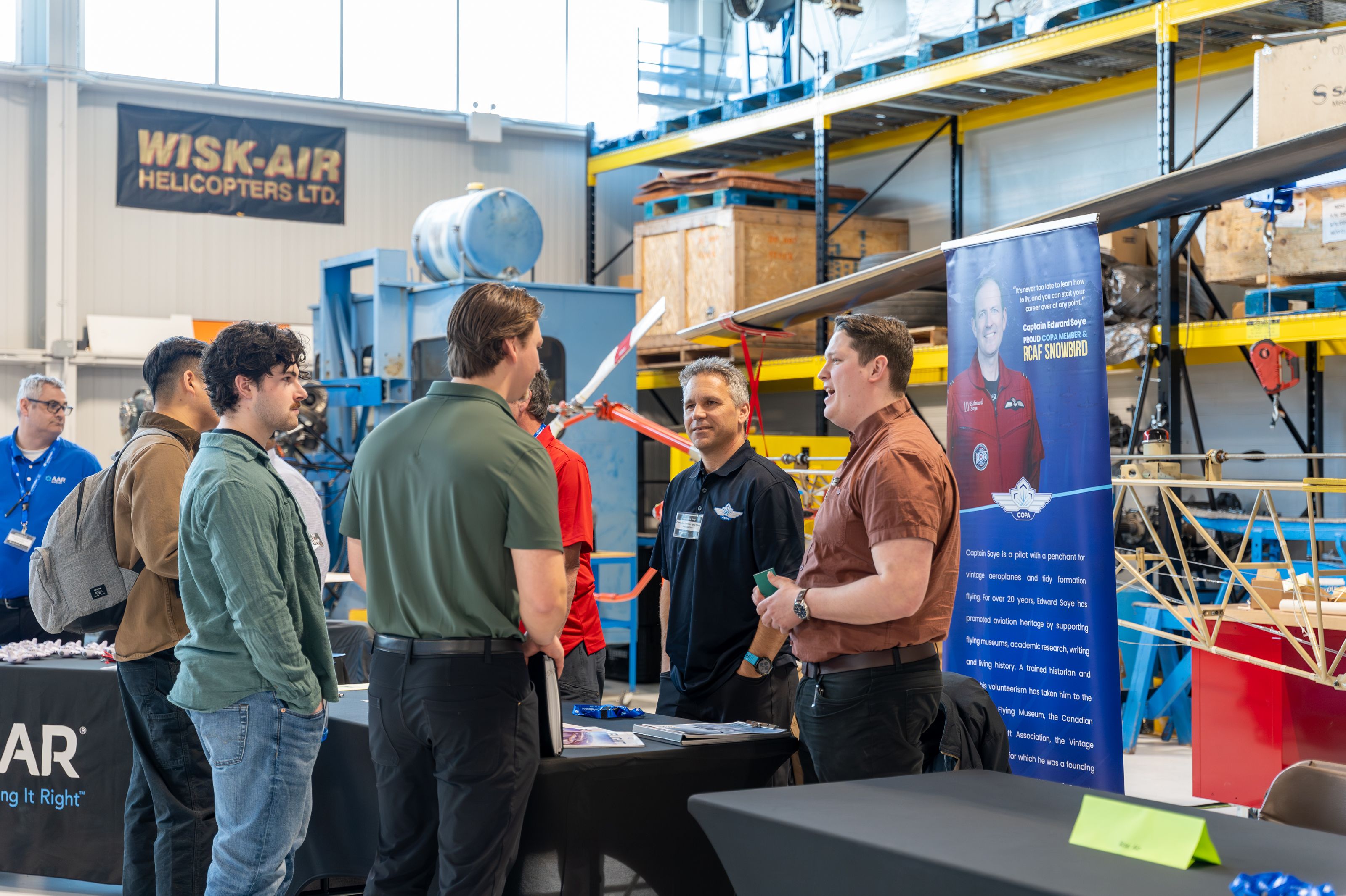 Students speak with aviation employers at Confederation College Aviation Day inside training hangar with aircraft equipment