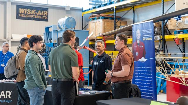 Students speak with aviation employers at Confederation College Aviation Day inside training hangar with aircraft equipment