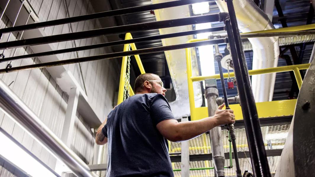 Student operating industrial equipment on an elevated platform during trades training