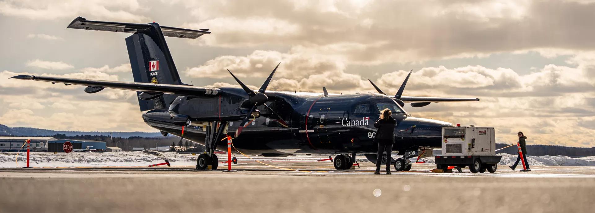 Royal Canadian Air Force aircraft on airport tarmac with ground crew and equipment