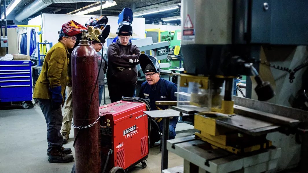 Instructor demonstrating welding techniques to students in a metal fabrication lab