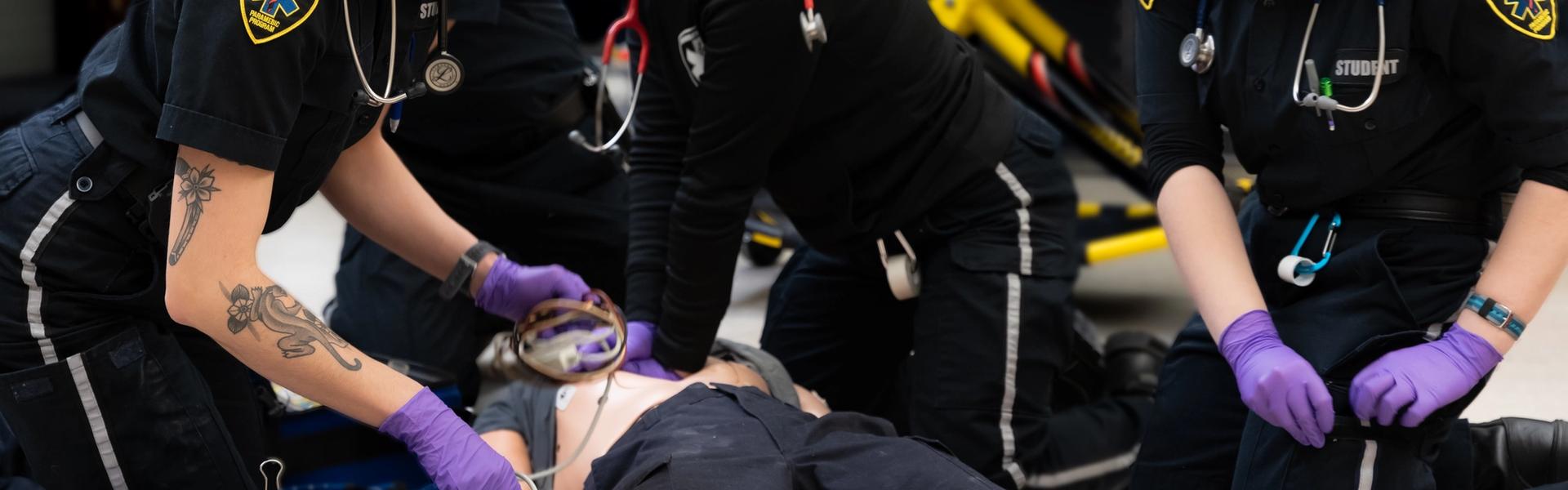 Team of paramedic trainees performing CPR and airway support in a lab setting