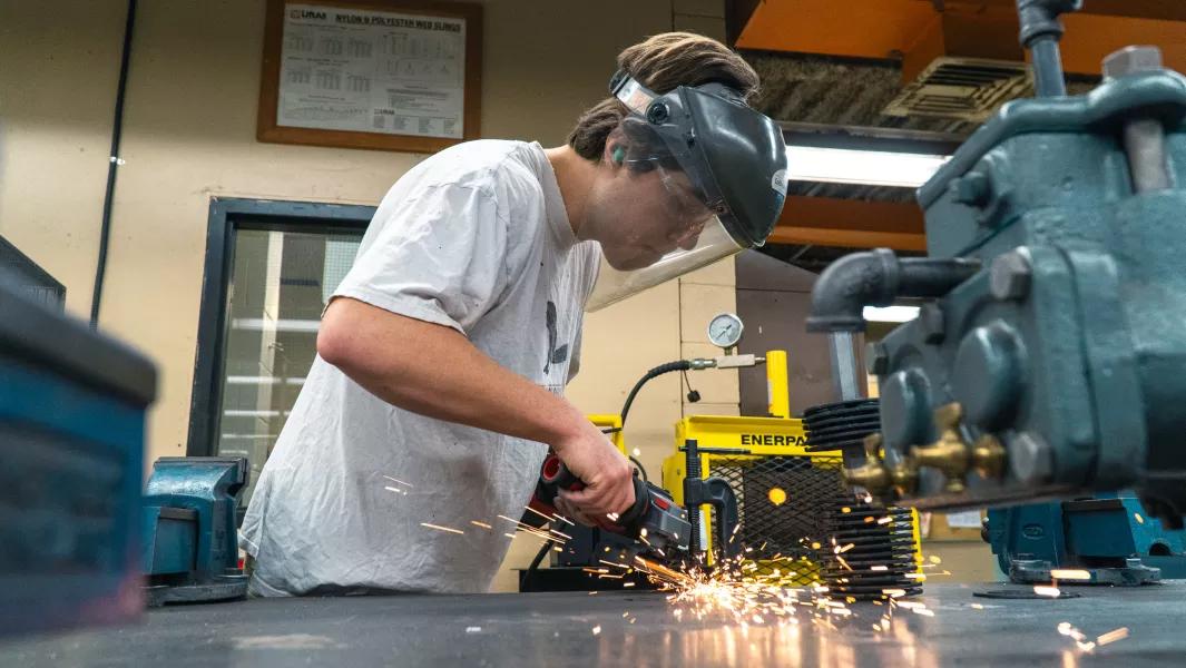 Student grinding metal with sparks flying