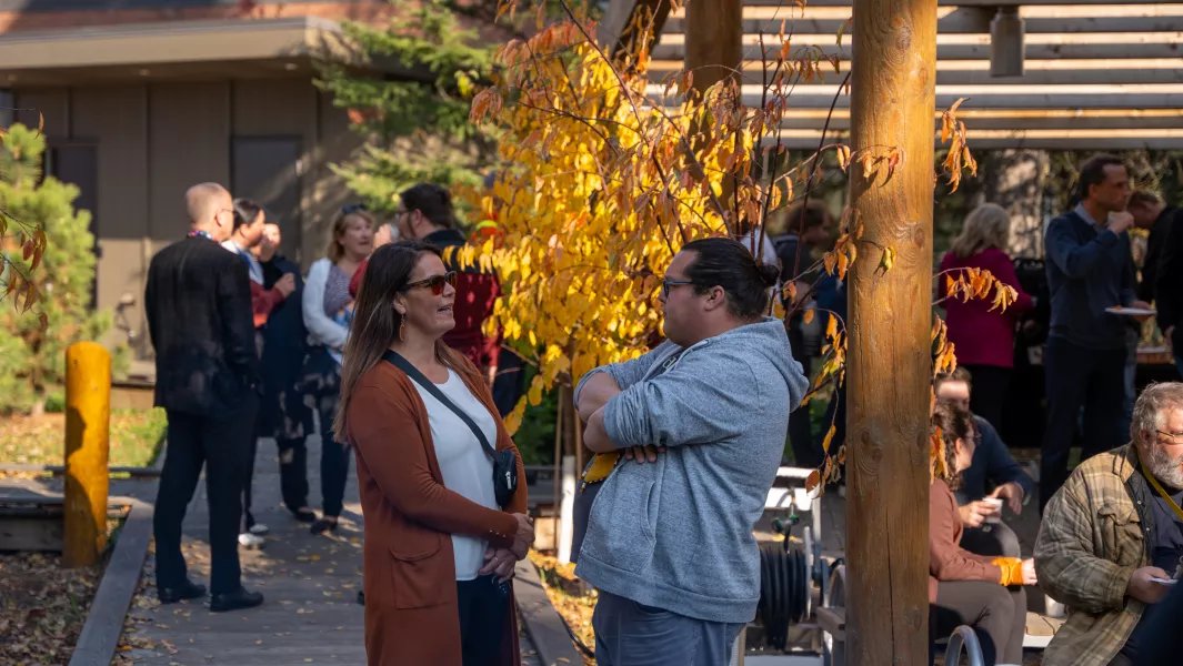 People talking and socializing outdoors near campus buildings in fall