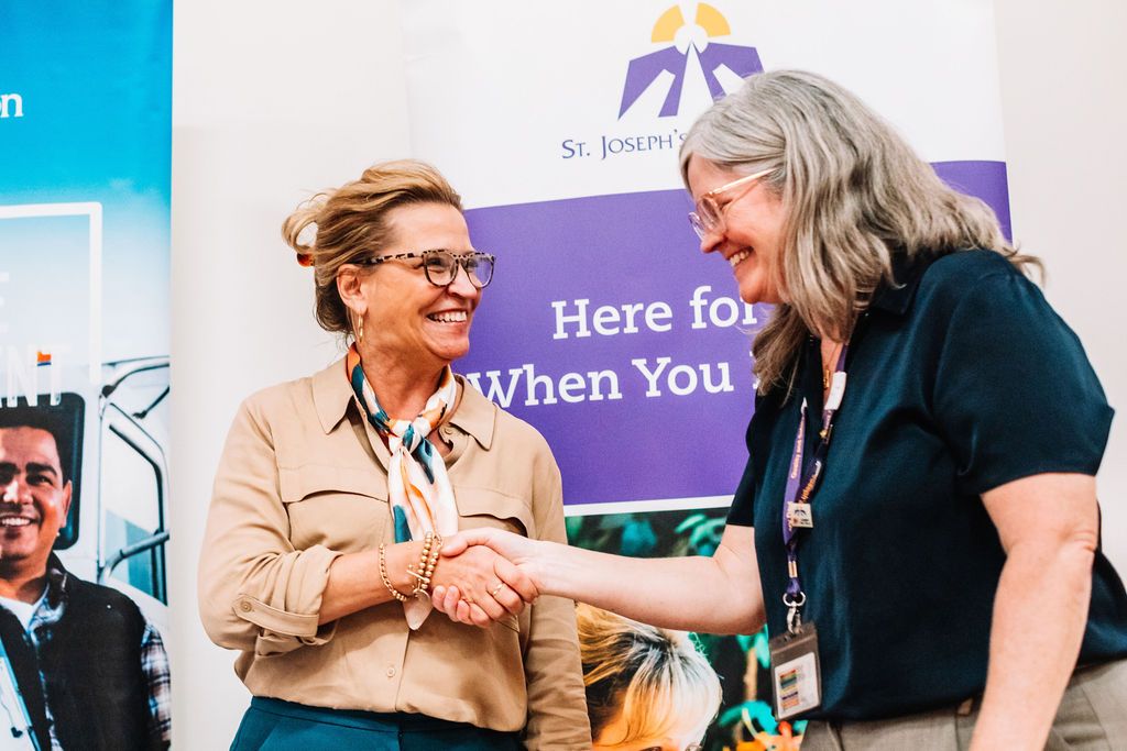 Two professionals shaking hands at a community partnership signing event