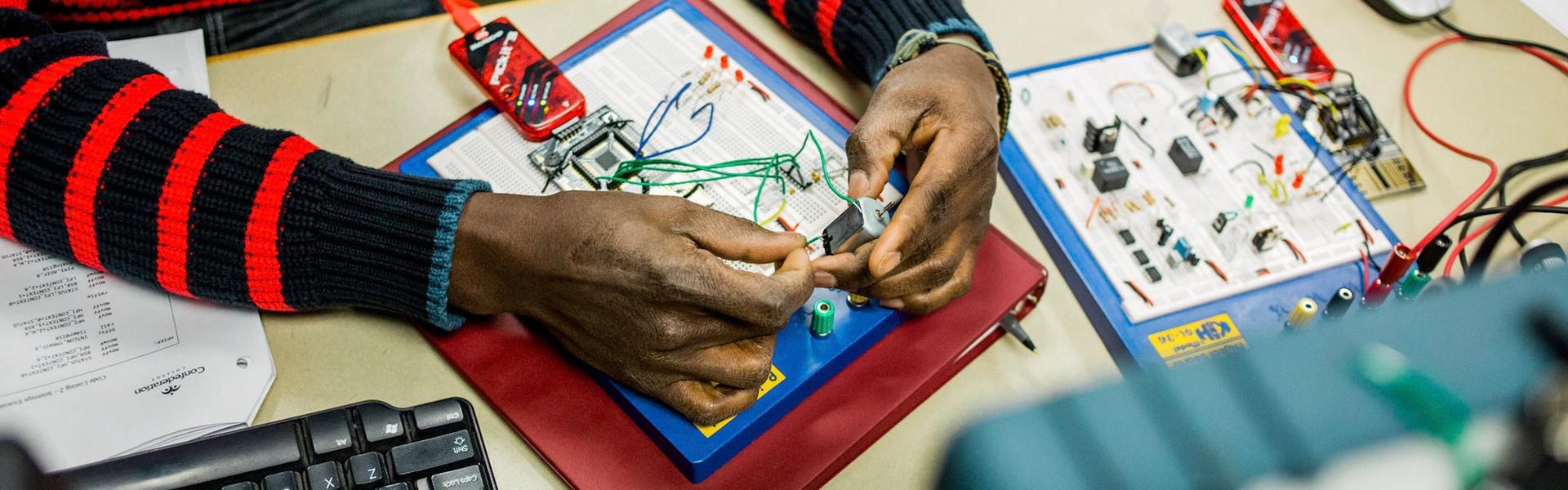 Student assembling circuitry on a breadboard in an electronics lab