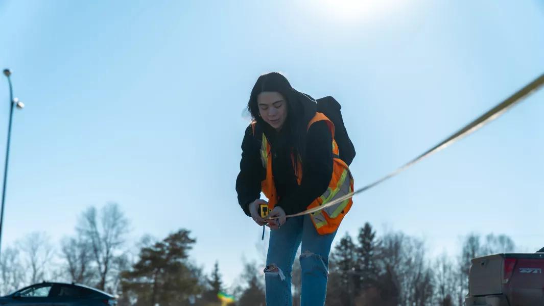 Student taking ground measurements with a tape measure during fieldwork