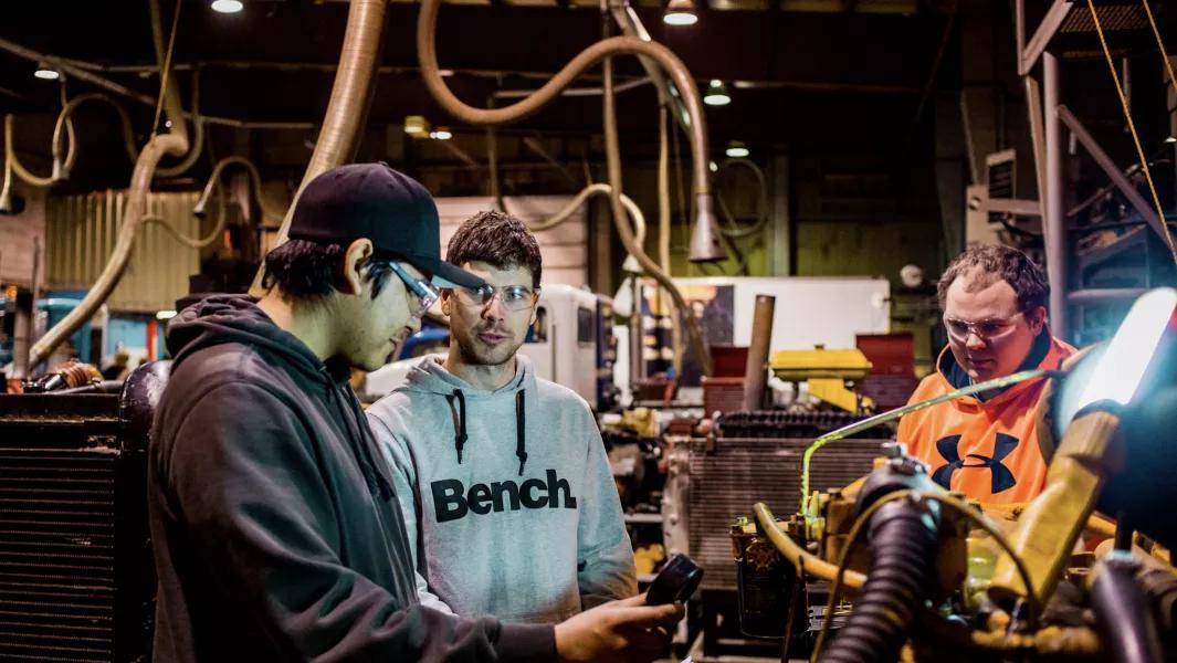 Manufacturing students reviewing machine operation and measurements together in an industrial lab