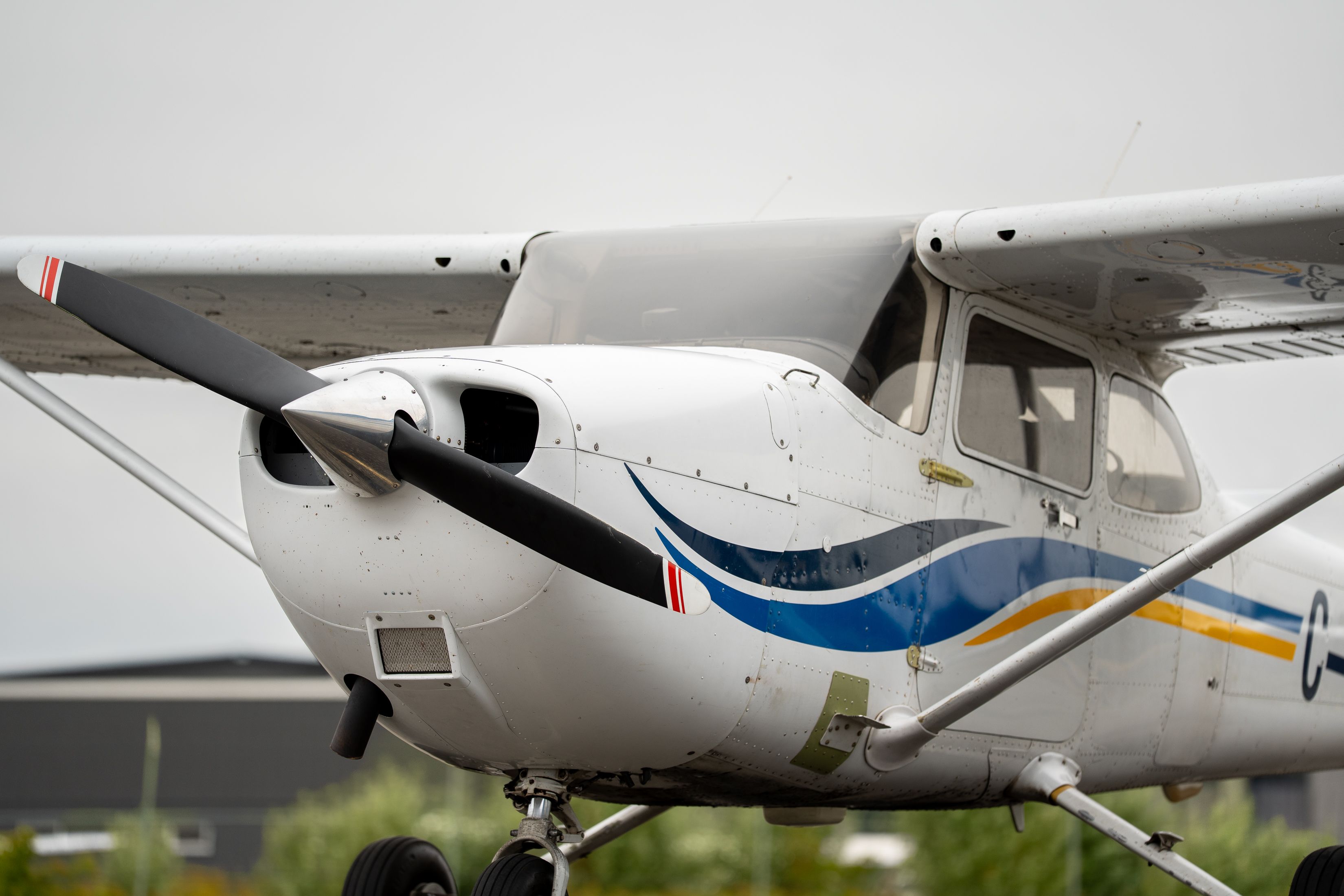 Close view of a white and blue single-engine airplane, with its black propeller, cockpit windows and landing gear visible.