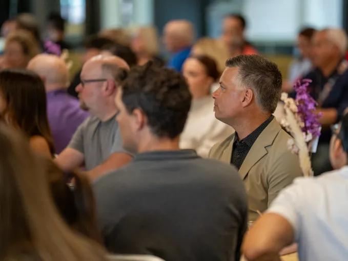 Audience members seated and listening at an indoor event