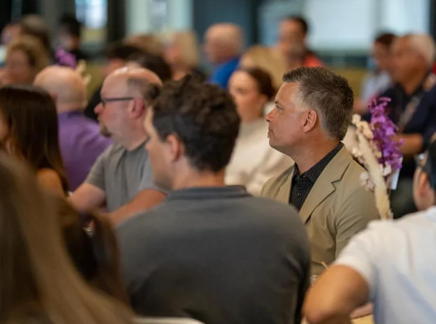 Audience members seated and listening at an indoor event