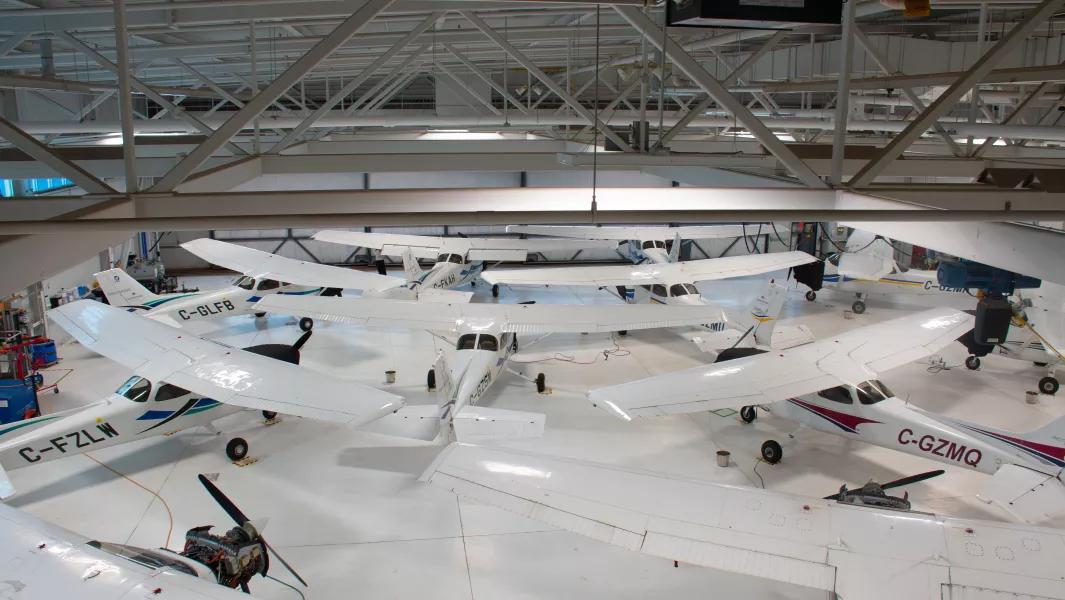 Multiple training aircraft lined up inside the aviation hangar