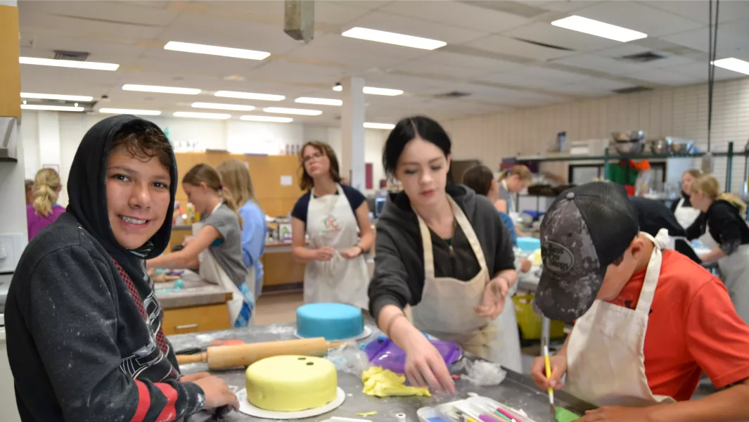 Youth decorating cakes in a baking activity during summer camp