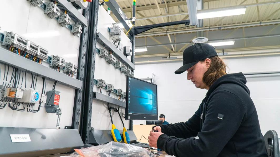Student assembling wiring at an electrical training panel