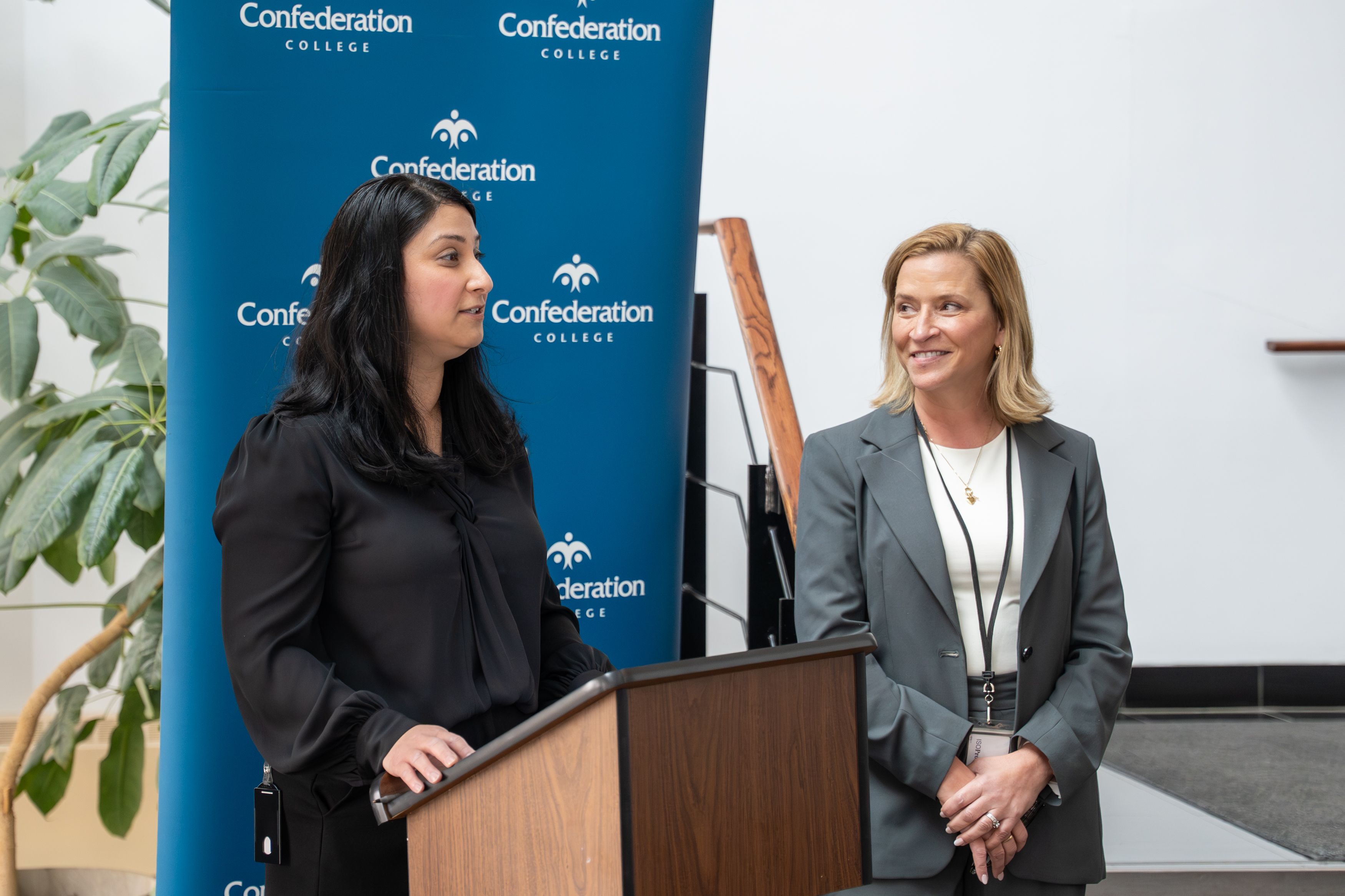 Two persons at podium during Confederation College announcement event with Alstom partnership backdrop