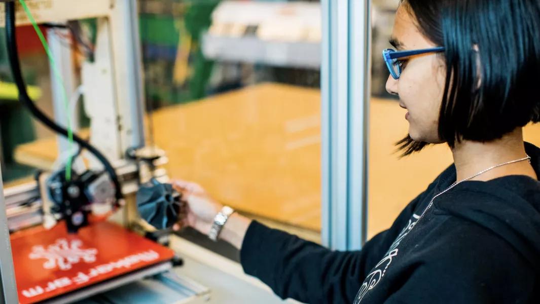 Student removing a completed part from a 3D printer