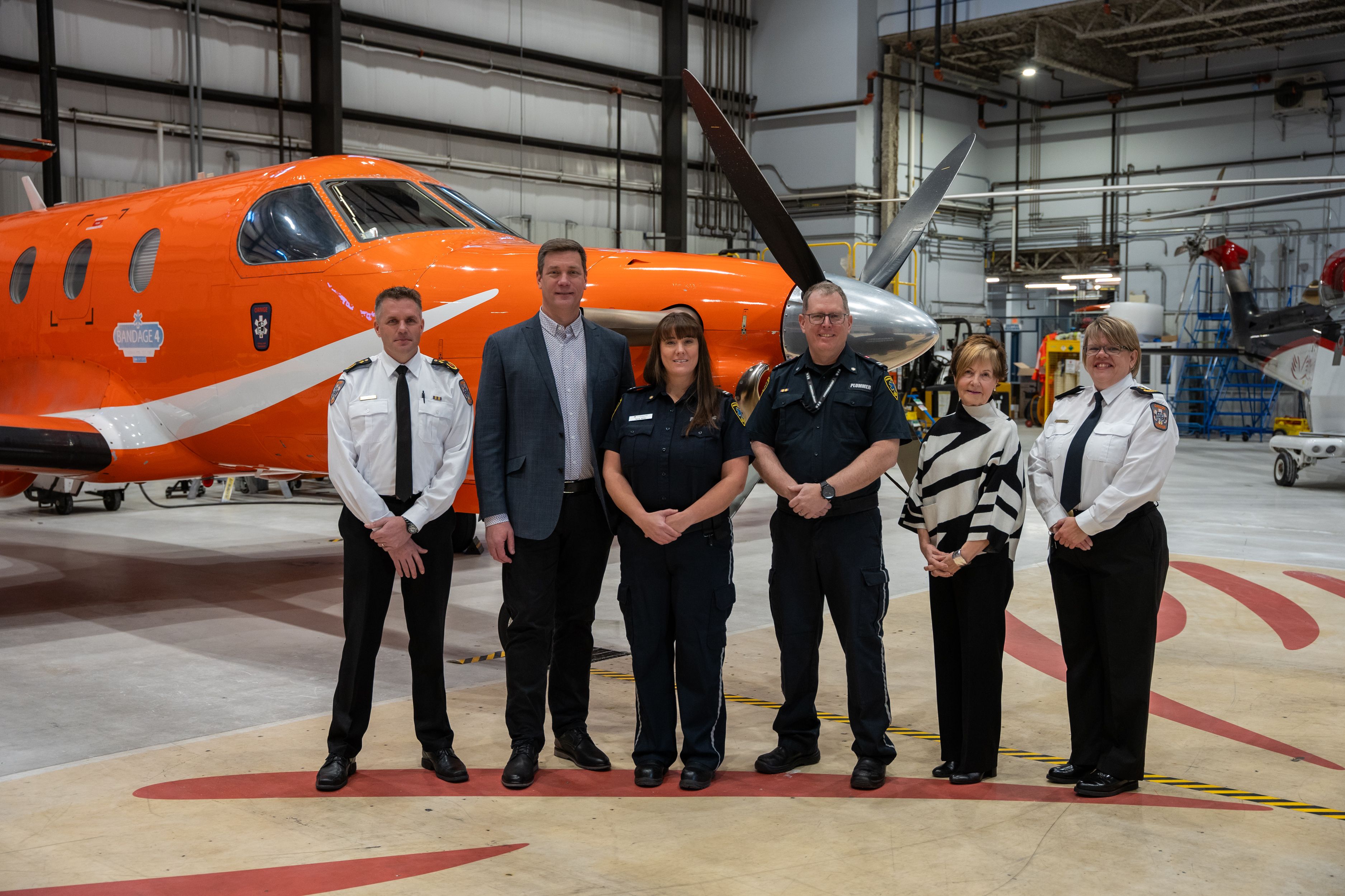 Ornge and Confederation College staff pose in front of an aircraft for the bursary announcement