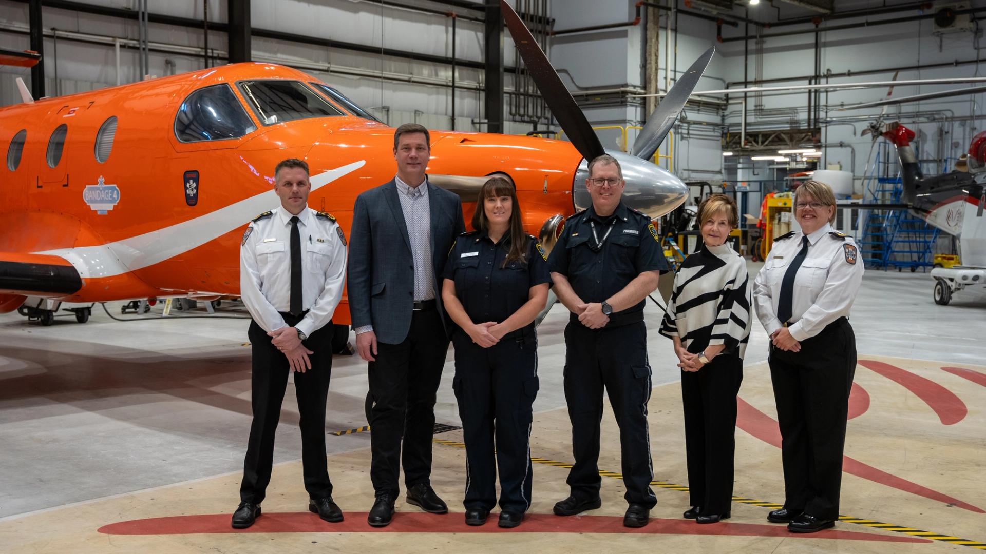 Ornge and Confederation College staff pose in front of an aircraft for the bursary announcement