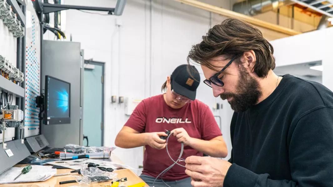 Students wiring components at an electrical workstation