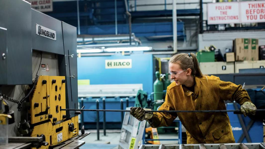 Student using industrial equipment to bend metal in the workshop